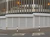 Several roller shutters in a row close off the understorey of a car park. The shutters are installed at slight angles to create a semi-circle.