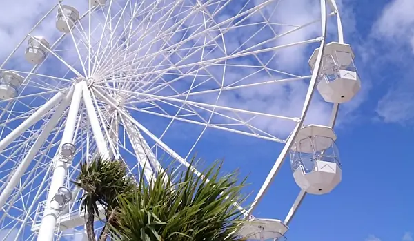A white ferriswheel seen from below against a clear blue sky