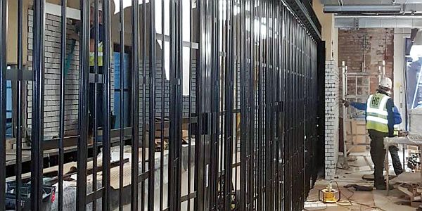 workmen next to a wall that houses a storage area for a sliding shutter