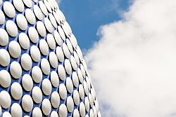 anodised aluminium discs on a curved blue surface, under a blue sky with white clouds