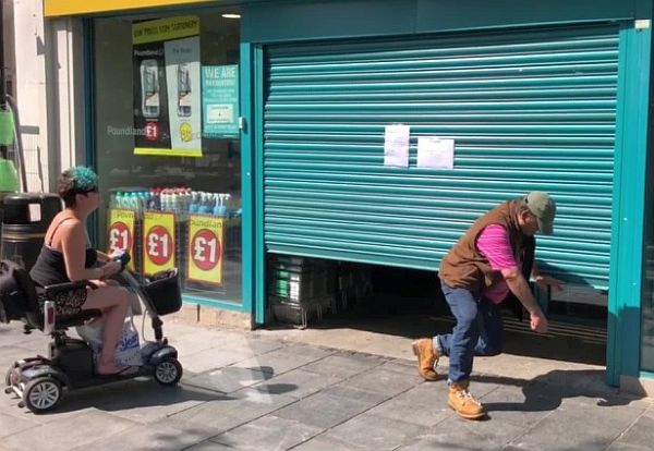 man crawling underneath a roller shutter