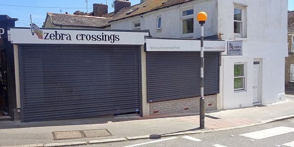 A set of two perforated steel roller shutters at a zebra crossings shop